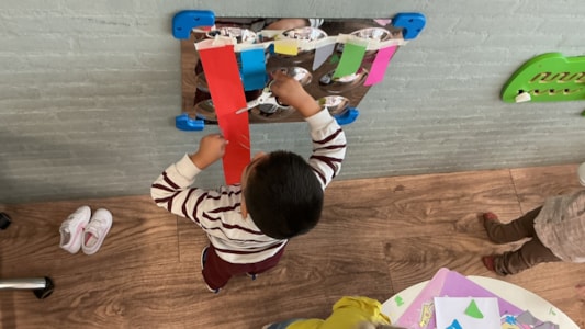 De peuters knippen en plakken de kleuren van het kleurenmonster. ✂️